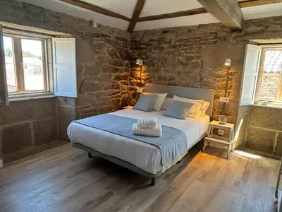 a bedroom with a bed with a stone wall at Casa Agolada in Golada
