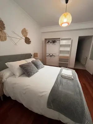 a bedroom with a large bed with a bench on it at La casa de Elena con terraza en el centro in Lugo