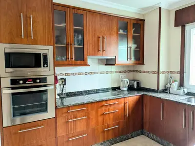 a kitchen with wooden cabinets and stainless steel appliances at Foz Beach Home in Foz