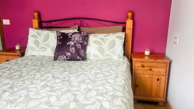 a bedroom with a bed and a purple wall at Foz Beach Home in Foz