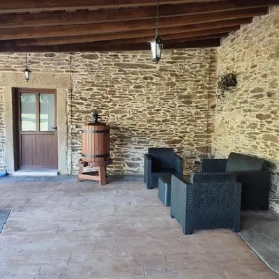 a patio with chairs and a wine barrel next to a brick wall at O Lar da Crega in O Pino