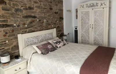 a bedroom with a bed and a stone wall at Estudios rúa Maior, 49-2B in Sarria