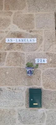 two signs on a brick wall with a plant at As Lamelas in Cea