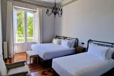 a bedroom with two beds and a chair and a window at Casa Palacio Ribeira Sacra in Esgos