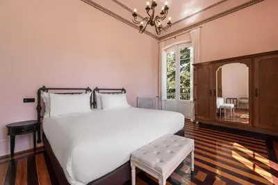 a bedroom with a large white bed and a chandelier at Casa Palacio Ribeira Sacra in Esgos