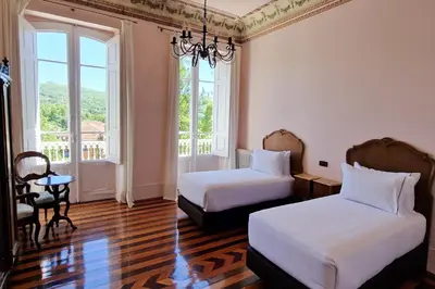 a room with two beds and a table and windows at Casa Palacio Ribeira Sacra in Esgos