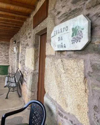 a sign on the side of a stone building with a bench at Casa Rural Santa Mariña in Portomarin