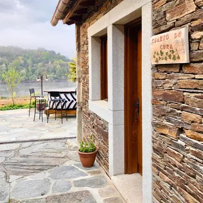 a stone building with a patio with a table and chairs at Casa Rural Santa Mariña in Portomarin
