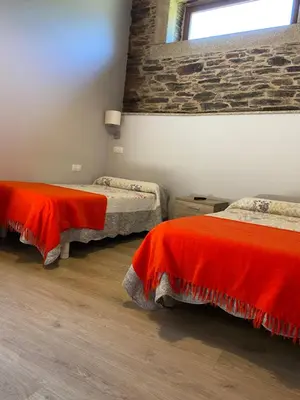 a room with two beds with red blankets on them at Casa Rural Santa Mariña in Portomarin