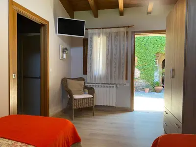 a bedroom with a bed and a chair and a sliding glass door at Casa Rural Santa Mariña in Portomarin