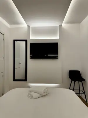 a bedroom with a white bed and a black chair at Kilometro 22 Luxury in Padrón