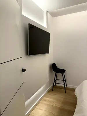 a bedroom with a tv on the wall and a stool at Kilometro 22 Luxury in Padrón