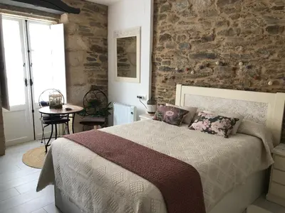 a bedroom with a bed and a stone wall at Estudios rúa Maior, 49-2A in Sarria