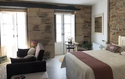 a bedroom with a bed and a chair and a table at Estudios rúa Maior, 49-2A in Sarria