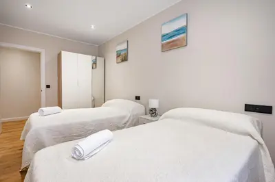 two beds in a room with white sheets at Apartamentos Marta in Ribadeo