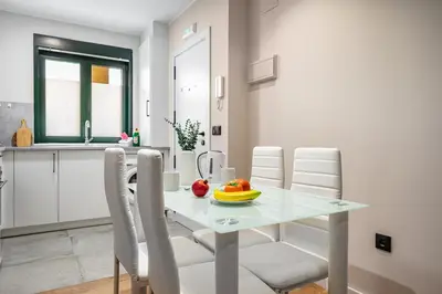 a white dining room table with white chairs and a bowl of fruit at Apartamentos Marta in Ribadeo