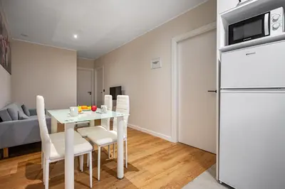 a kitchen and dining room with a table and a refrigerator at Apartamentos Marta in Ribadeo