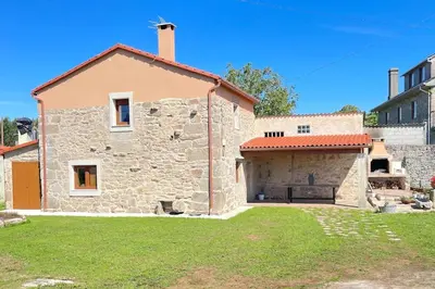 a large stone building with a garage in a yard at A Casa Do Cuarto in Irijoa
