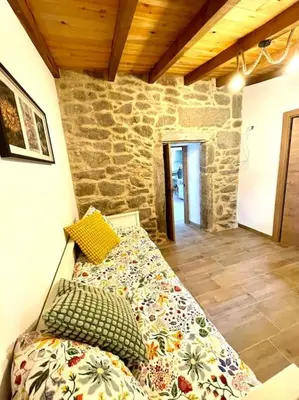 a bed in a room with a stone wall at A Casa Do Cuarto in Irijoa