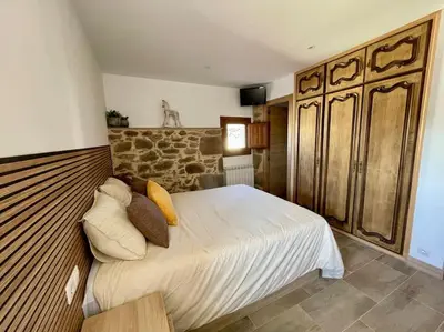 a bedroom with a bed and a stone wall at A Casa Do Cuarto in Irijoa