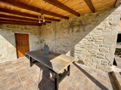 a wooden table in a room with a stone wall at A Casa Do Cuarto in Irijoa