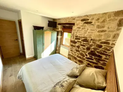 a bedroom with a stone wall and a bed at A Casa Do Cuarto in Irijoa