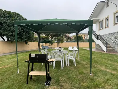 a table and chairs under a green canopy with a laptop at Chalet Abelleira Playa Barreiros in Barreiros