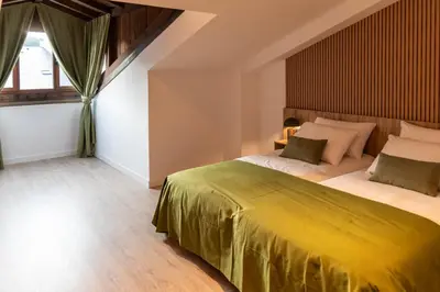 a bedroom with a large bed with a yellow bedspread at Hotel & Restaurante El Casino in Villafranca del Bierzo