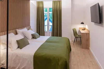 a bedroom with a bed and a desk and a window at Hotel & Restaurante El Casino in Villafranca del Bierzo