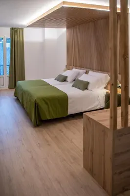 a bedroom with a large bed with a green blanket at Hotel & Restaurante El Casino in Villafranca del Bierzo