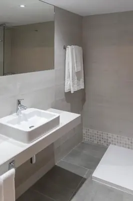a white bathroom with a sink and a mirror at Hotel & Restaurante El Casino in Villafranca del Bierzo