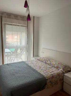 a bedroom with a bed and a window with a table at Piso cerca de la playa, dos habitaciones, piscina y terraza in San Ciprián