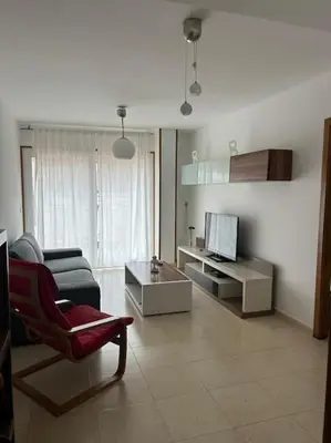 a living room with a couch and a tv at Piso cerca de la playa, dos habitaciones, piscina y terraza in San Ciprián