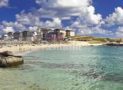 a beach with a group of people in the water at Piso cerca de la playa, dos habitaciones, piscina y terraza in San Ciprián