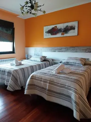 two beds in a room with orange walls at Vivienda turistica Os Galegos en Palas de Rey in Palas de Rei