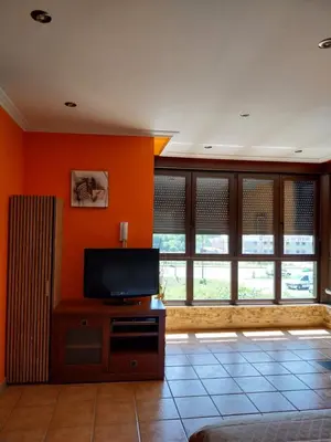 a living room with orange walls and a flat screen tv at Vivienda turistica Os Galegos en Palas de Rey in Palas de Rei