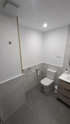 a white bathroom with a toilet and a sink at Alojamiento Las Nogueiras in La Caridad