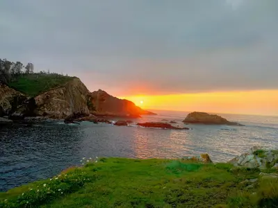 a sunset over a body of water with the sun setting at Alojamiento Las Nogueiras in La Caridad