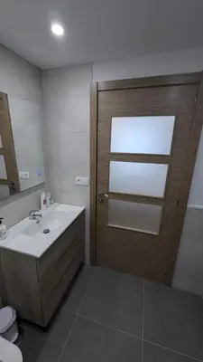 a bathroom with a wooden door and a sink at Alojamiento Las Nogueiras in La Caridad