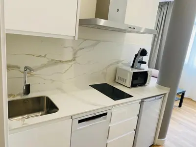 a white kitchen with a sink and a microwave at Apartamentos Buenos Aires,en el centro de Ribadeo con vistas a la ría in Ribadeo