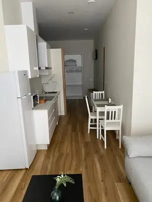 a kitchen and a living room with a table and chairs at Apartamentos Buenos Aires,en el centro de Ribadeo con vistas a la ría in Ribadeo