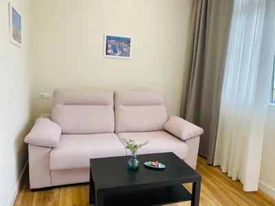 a living room with a pink couch and a table at Apartamentos Buenos Aires,en el centro de Ribadeo con vistas a la ría in Ribadeo