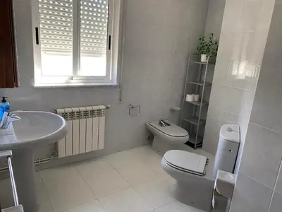 a white bathroom with a toilet and a sink at Ático Calvo Sotelo 217 in Sarria