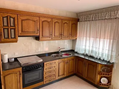 a kitchen with wooden cabinets and a sink at Ático Calvo Sotelo 217 in Sarria