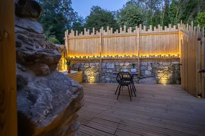 a patio with a wooden fence and a table and a chair at as Alvarizas in Moraña