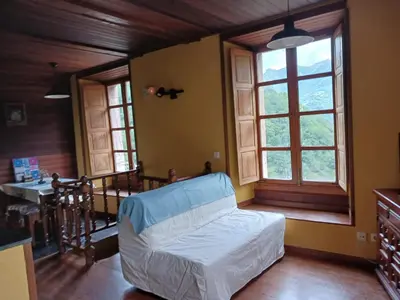 a bedroom with a bed and a table and windows at Casa del OSO2 in Pola de Somiedo