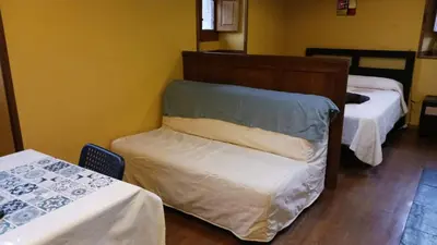 a room with two beds and a chair in it at Casa del OSO2 in Pola de Somiedo