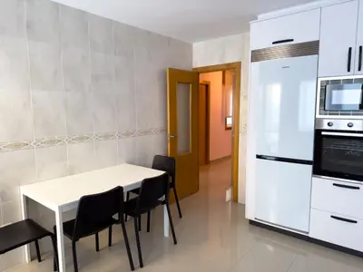 a kitchen with a white table and chairs and a refrigerator at O Nido de Noe in Melide