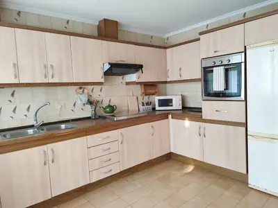 a kitchen with wooden cabinets and a sink and a microwave at Piso de Alba in Chantada