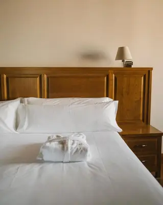 a white bed with a wooden headboard and white sheets at Pazo Arretén in Padrón